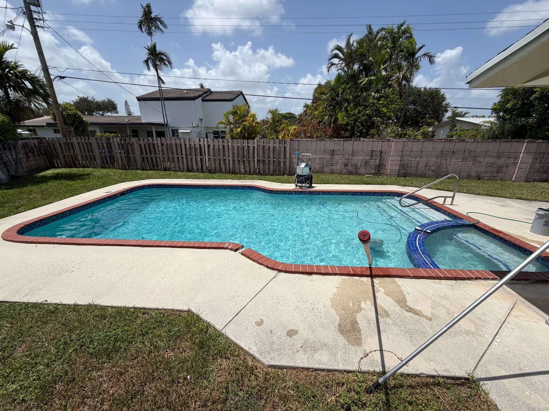 Rectangular pool with red brick coping and blue tile spa in South Florida