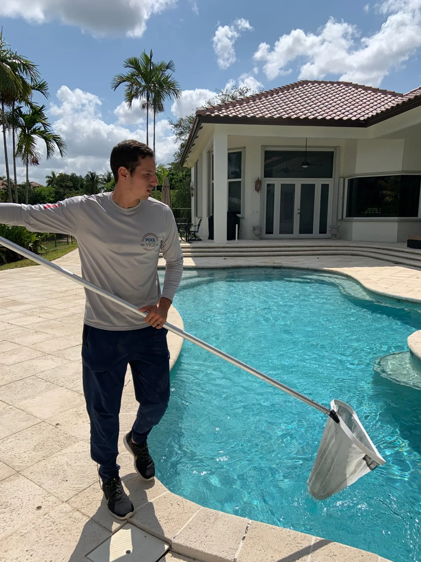 Pool Vice technician skimming a residential pool in South Florida